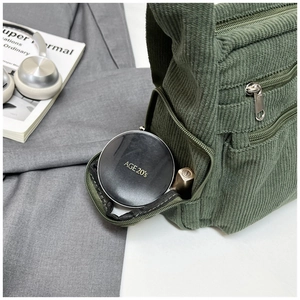 Détail du sac en velours côtelé vert montrant la poche zippée avec du maquillage