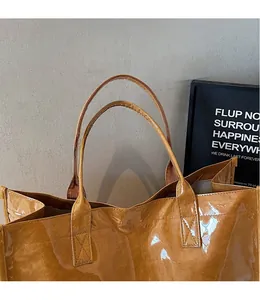 Detail of caramel Tyvek tote bag featuring glossy crinkled texture and reinforced handles