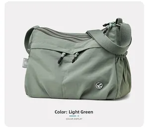 Detail view of water-resistant light green nylon crossbody bag with multi-zipper pockets