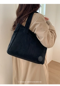 Detail of minimalist black suede tote bag with circular logo and fine matte texture