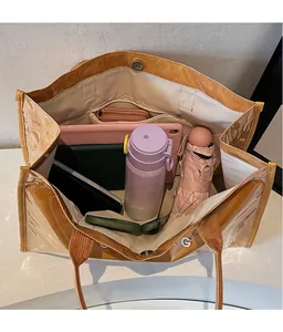 Detail view of the spacious inner compartment of the brown tote bag with various items