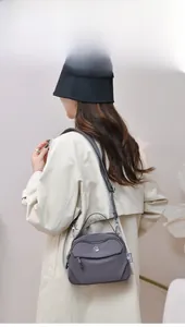 Vue latérale d'un sac bandoulière en nylon gris foncé porté par un mannequin