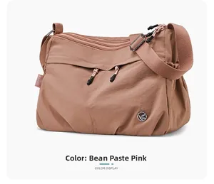 Detail view of pink water-resistant nylon crossbody bag with multi-zipper compartments