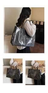 Detail of a black glossy tote bag with white TOTE BAG lettering and double handles