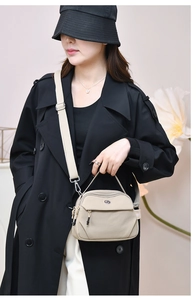 Détail du sac bandoulière en nylon beige avec zips et sangle réglable porté par un mannequin
