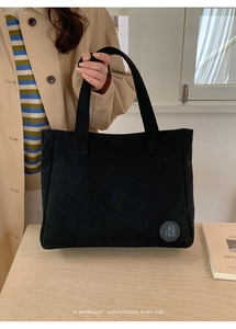 Detail of a black retro tote bag with an embossed logo and soft suede-like texture