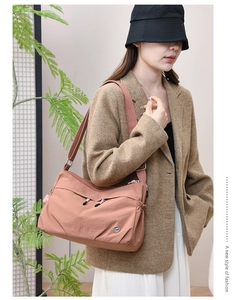 Detail of pink-brown waterproof nylon crossbody bag featuring multiple zipper pockets
