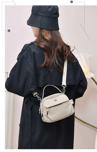 Détail arrière d'un sac à bandoulière en nylon beige avec large sangle en tissu
