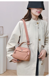 Vue détaillée du sac bandoulière en nylon rose avec logo en métal et sangle réglable