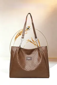 Detail of woven leather texture on large brown tote bag with decorative metal chain