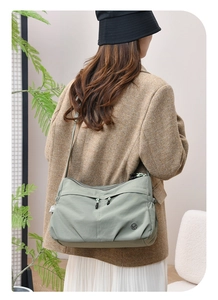 Close-up of light green water-resistant nylon crossbody bag with dual zippers and logo