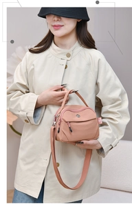 Gros plan du sac bandoulière en nylon rose clair avec fermetures éclair et étiquette
