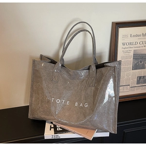 Detailed view of taupe tote bag with glossy finish and white TOTE BAG lettering print