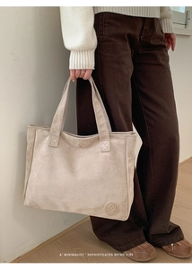 Detail showing the embossed logo and soft suede texture of this beige minimalist tote bag