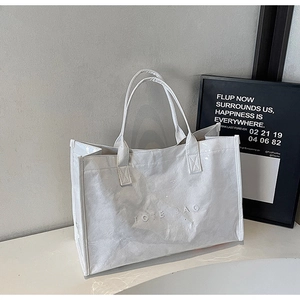 Detail of white Tyvek tote bag featuring a textured finish and embossed TOTE BAG text