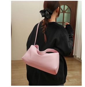 Pink lychee grain leather crossbody bag shown on model in a cozy indoor setting