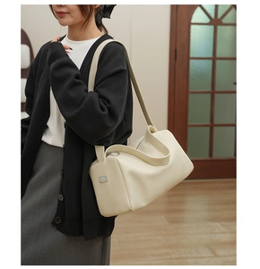Close-up of cream-colored litchi grain leather shoulder bag with metallic buckle detail