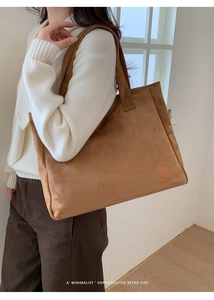 Detail of retro brown suede tote bag showing minimalist logo and fine leather texture