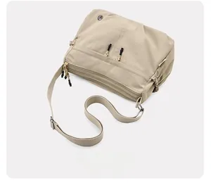 Top view of beige water-resistant nylon crossbody bag with multi-zippered compartments