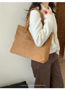 Close-up of brown suede tote bag featuring a minimalist circular embossed logo detail