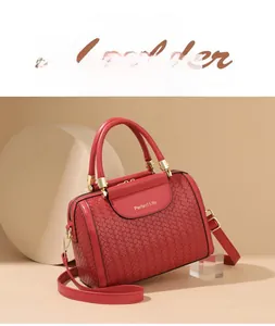 Detail shot of a red woven leather handbag with gold metal hardware and brand engraving