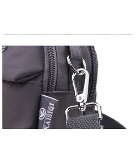 Détail du fermoir mousqueton en métal argenté et de l'anneau en D sur le sac en nylon gris
