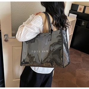 Detail of a black glossy tote bag with white text held by a model in a cozy setting