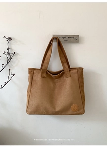 Detail of vintage brown suede tote bag showing soft texture and leather logo patch