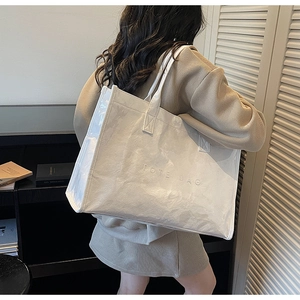 Detail of white Tyvek tote bag with embossed text and clear PVC side seam trim