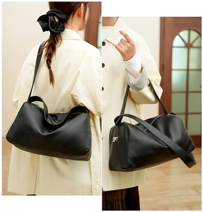 Close-up of black lychee grain leather shoulder bag with wide strap and metallic logo