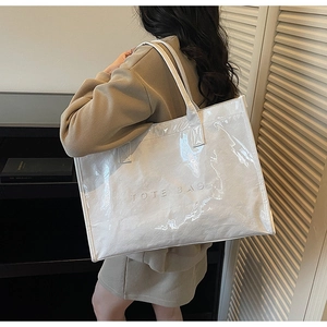 Close-up of a glossy creamy white Tyvek tote bag with embossed TOTE BAG lettering detail
