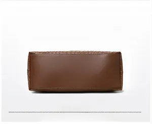 Detail view of the brown woven tote bag's bottom featuring precise stitching and texture