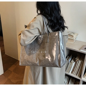 Side view of a grey translucent tote bag worn by a model in a cozy interior