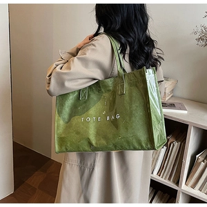 Detail shot of a green high-capacity tote bag with TOTE BAG print on a model