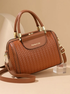 Detailed close-up of woven caramel leather tote with gold hardware and logo engraving
