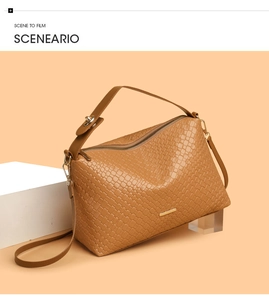 Detail of tan woven texture on a minimalist shoulder bag with gold metal hardware accent