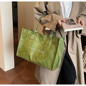 Detail of green Tyvek tote bag with glossy finish and white TOTE BAG lettering text