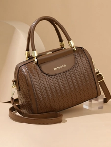 Detailed view of dark brown woven Boston bag with gold hardware and logo engraving