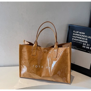 Detail of a brown tote bag with PVC transparent outer layer and TOTE BAG print