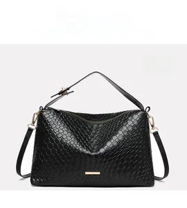 Close-up of black woven leather tote featuring gold zipper and metal decorative bar