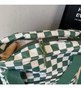 Detail of green and white checkered tote bag featuring a smooth metal zipper closure