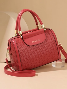 Detailed close-up of red woven leather tote bag featuring gold logo and metallic hardware