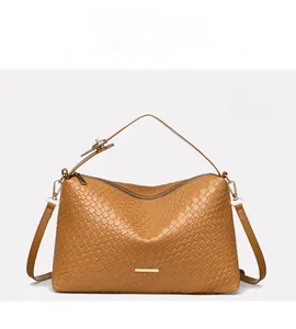 Macro detail of light brown woven leather handbag texture with minimalist metal logo plaque