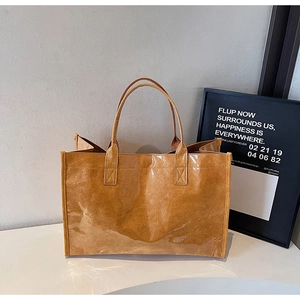 Detail of a brown Tyvek tote bag featuring a trendy transparent PVC waterproof outer layer