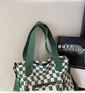 Detail of green checkerboard corduroy tote bag with durable woven handles and zipper pockets
