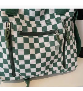 Detail of green checkerboard corduroy tote featuring multiple zipper pockets with knots