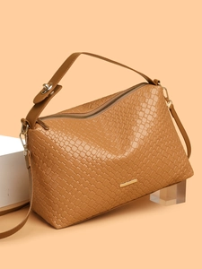 Detail of caramel woven texture on shoulder bag with metal zipper and adjustable strap