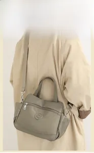 Model wearing a grey-green nylon crossbody bag with multi-layer pockets and logo detail