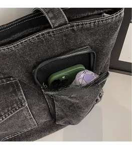 Close-up of black denim tote bag with white stitching, zipper pocket, and storage capacity