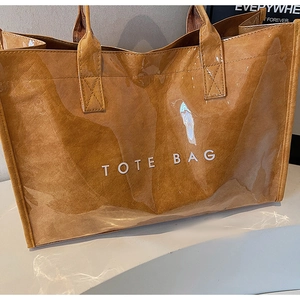 Detail of Tyvek tote bag with transparent PVC shell and brown inner pouch on stone surface